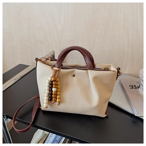 Detail of cream canvas tote with brown leather handles and decorative wooden beads