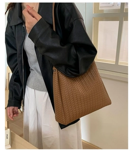 Detail showing brown woven texture on large hobo tote bag held by a model