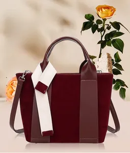 Detailed view of burgundy velvet bucket bag with wide cream strap and silver hardware
