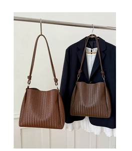 Detail of dark brown woven tote bag with knotted strap and Intrecciato craftsmanship