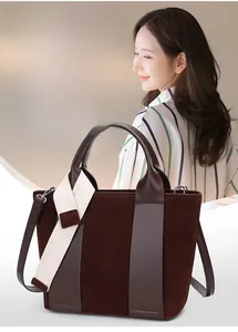 Detail of dark brown patchwork bucket bag with suede texture and wide canvas strap