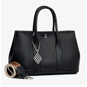 Detail of black lychee grain leather tote with silver hardware and woven shoulder strap