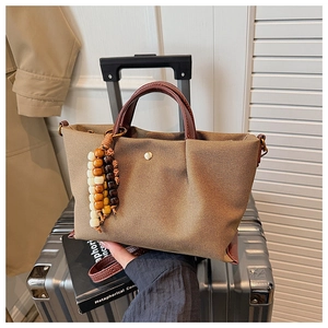 Detailed macro view of brown canvas tote bag with leather straps on a silver suitcase