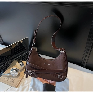 Détail d'un sac à main en daim marron foncé avec logo de marque et boucle métallique