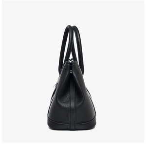 Close-up of black lychee leather texture and sturdy stitching on a tote bag side view