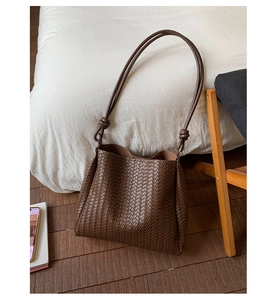 Macro detail of brown woven leather texture and bucket bag strap on wooden floor