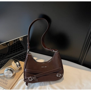 Détail du sac croissant marron foncé avec patchwork de cuir et décoration de nœud latéral