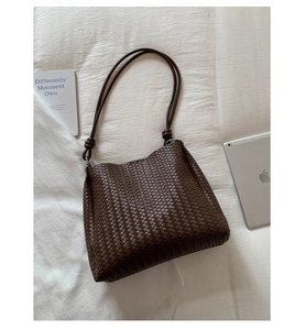 Detail view of woven leather shoulder bag with intricate texture and decorative knot strap