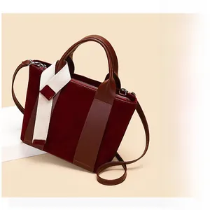 Detailed view of burgundy suede patchwork tote bag with brown handles and white fabric strap