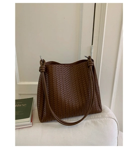 Detailed close-up of brown woven leather texture and knotted strap with silver ring
