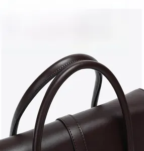 Detail of reinforced handles and fine stitching on a dark brown leather tote bag