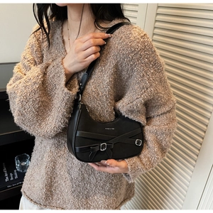 Détail du sac selle noir avec nœud et boucle argentée sur un pull marron