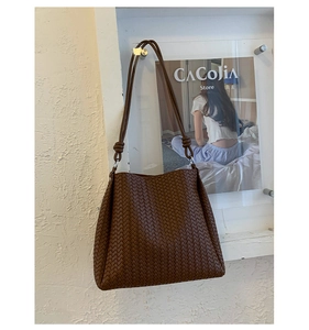 Macro detail of dark brown woven texture and stylish knotted shoulder straps on a bucket bag