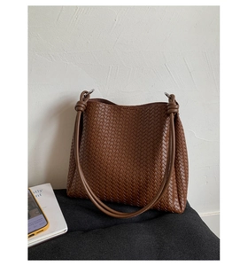 Detail of hand-woven brown leather texture and knotted strap on bucket bag