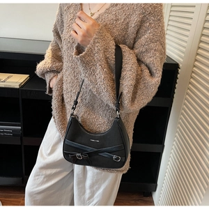 Détail du sac demi-lune noir avec nœud décoratif et boucle argentée sur le mannequin