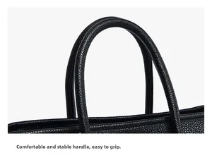 Detail shot of black litchi pattern leather tote handle with sturdy stitching