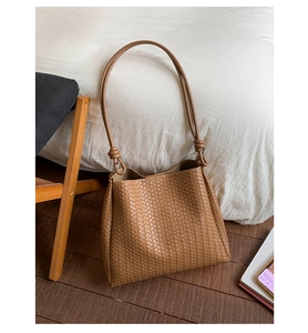 Close-up of brown woven bucket bag featuring intricate Intrecciato leather texture and knots