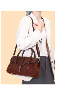 Detail view of large brown leather tote bag with metal buckle worn on model shoulder