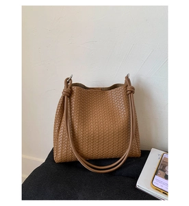 Detailed view of brown woven leather bucket bag with knotted shoulder strap and soft texture