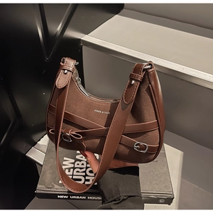 Détail d'un sac hobo marron en patchwork de cuir avec boucle en métal et lanières