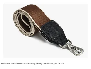 Detail view of wide woven canvas bag strap with leather ends and silver metal lobster clasps