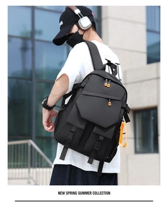 Detail of black tactical backpack with orange contrast zippers and multi-pocket design