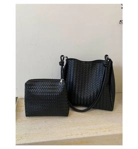 Detail shot of woven bucket bag and matching pouch on a marble surface with minimalist backdrop