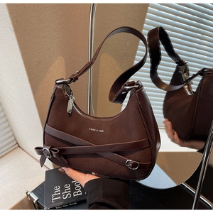 Détail du sac croissant en daim marron foncé avec boucles en métal et texte logo