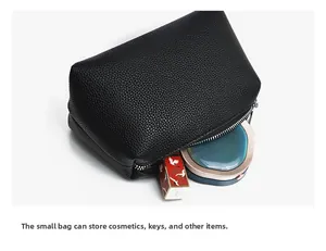 Detail view of black lychee grain leather pouch with silver zipper and inner space