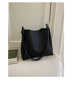 Detail of black woven leather shoulder bag showing intricate texture and knotted straps