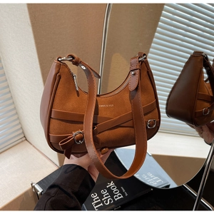 Détail du sac bandoulière en daim marron avec boucle en métal et lanières croisées