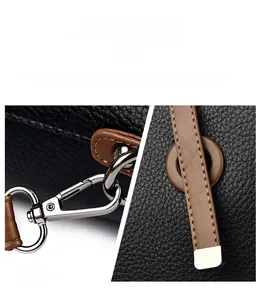 Detail of silver hardware latch and brown trim on black lychee grain leather tote bag