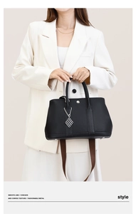 Detail of black pebbled leather tote with silver buckle and wide canvas shoulder strap