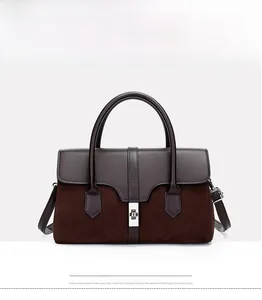 Front detail of a two-tone leather handbag with a silver twist lock and suede paneling