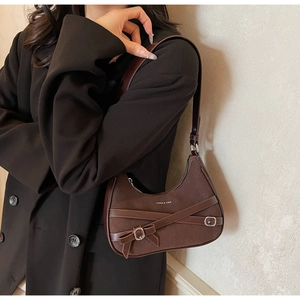 Détail d'un sac bandoulière vintage en daim marron foncé avec boucle en métal noeud