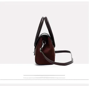 Detail of burgundy paneled handbag showing suede side texture and metallic buckle strap