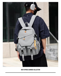 Detail of light gray multi-pocket backpack with orange pullers and buckle straps
