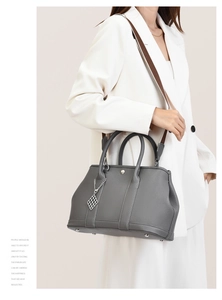 Detail of grey pebbled leather tote with adjustable wide strap and silver pendant
