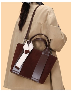 Detail of vintage brown patchwork tote bag with contrast strap worn over a trench coat