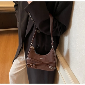 Gros plan d'un sac à bandoulière en daim marron avec nœud et détails en cuir sur modèle