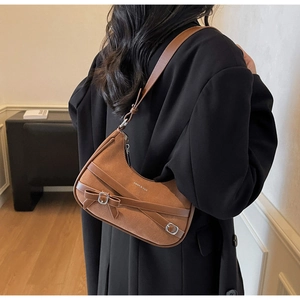 Sac demi-lune en daim marron avec nœud et détails argentés porté par un mannequin