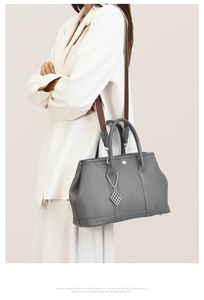 Close-up of grey lychee textured leather tote bag with stylish wide woven strap