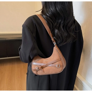 Détail du sac demi-lune en daim marron avec sangles croisées et boucles en métal