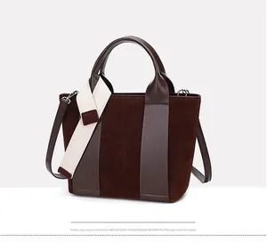 Detail of dark brown patchwork bucket bag with suede texture and leather straps