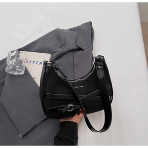 Détail d'un sac demi-lune noir avec boucle nœud et textures de cuir mélangées