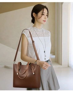 Detailed shot of brown litchi leather tote bag with silver hardware on fashion model