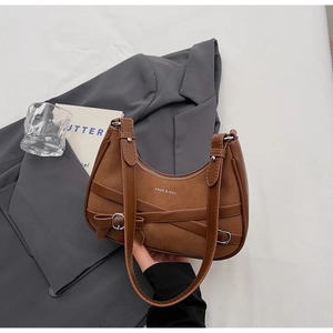 Détail d'un sac bandoulière en daim marron avec sangles croisées et boucle en métal