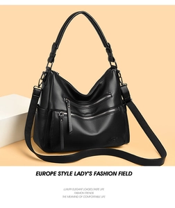 Detail of black pebbled leather handbag with double zipper accents and adjustable strap