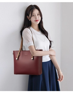 Detail view of burgundy leather tote bag with brown straps and kangaroo logo engraving