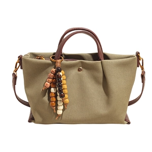 Military green canvas tote bag with brown leather handles and wooden bead tassel decor